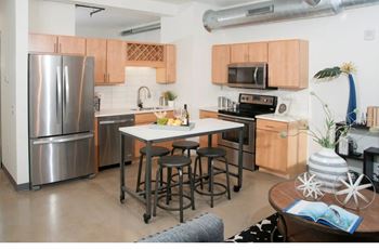A kitchen with a refrigerator, microwave, oven, and sink.